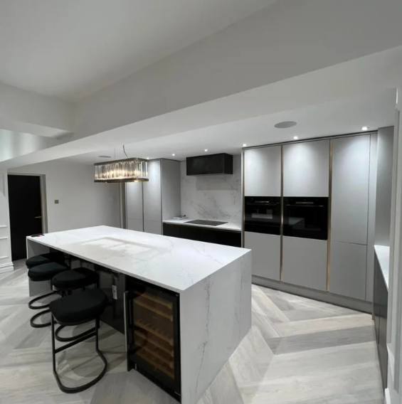 White handleless kitchen with marble island, wine cooler and pendant lighting, fitted by JL Kitchens & Bedrooms
